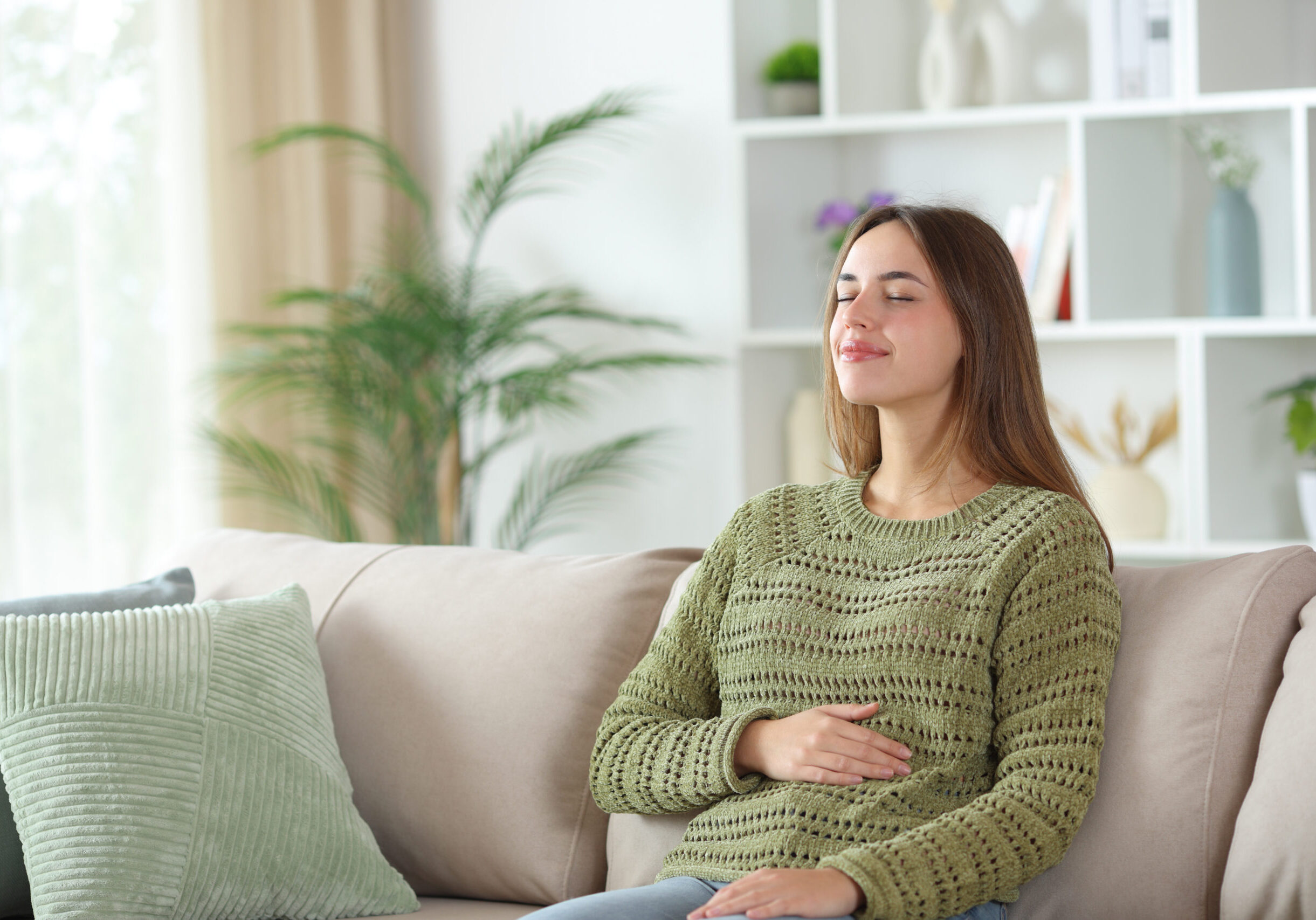 Woman enjoying a healthy bowel tract sitting on a couch at home