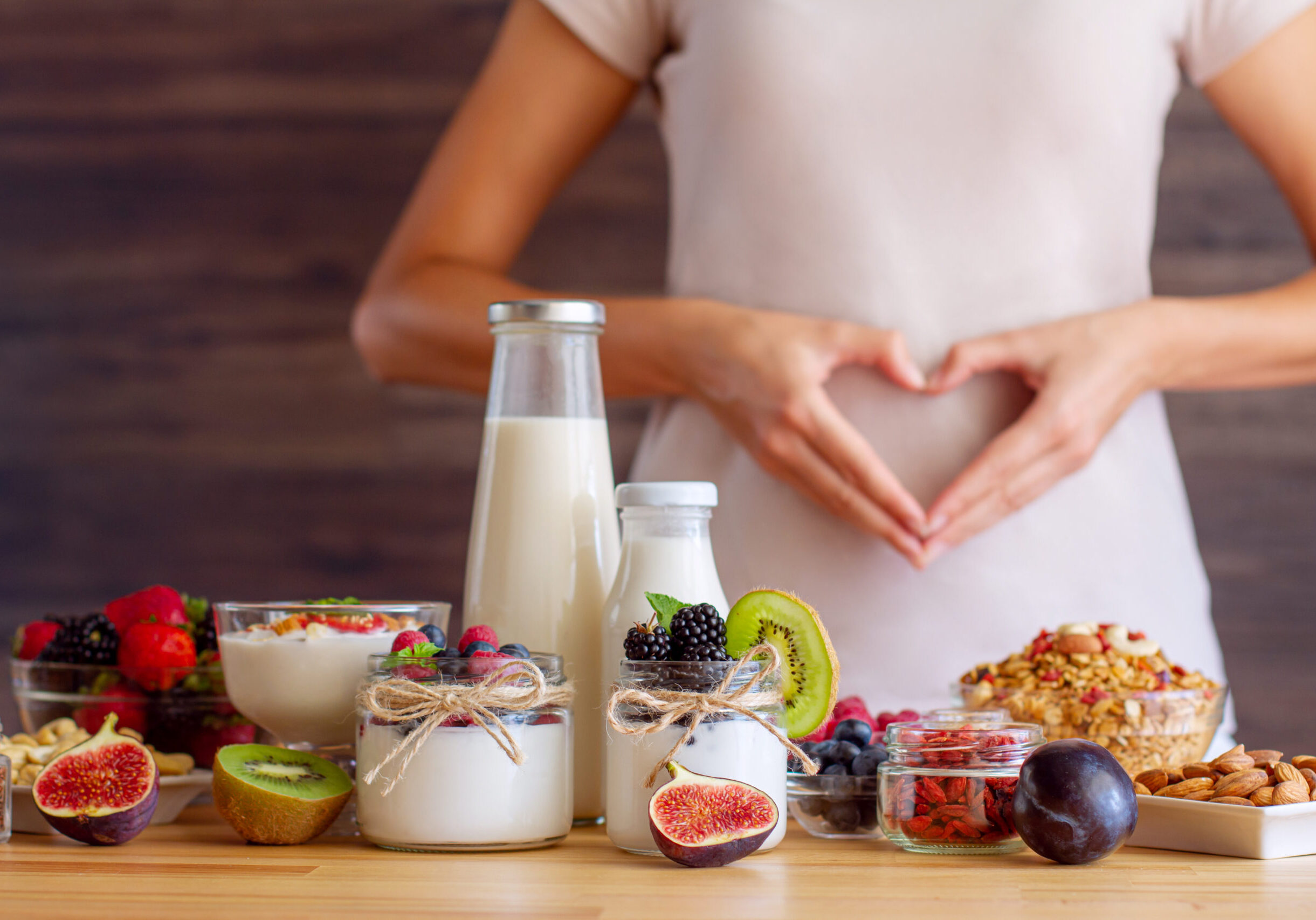 Female make shape of heart with her hands. Light summer breakfast with organic yogurts, fruits, berries and nuts. Nutrition that promotes good digestion and functioning of gastrointestinal tract.